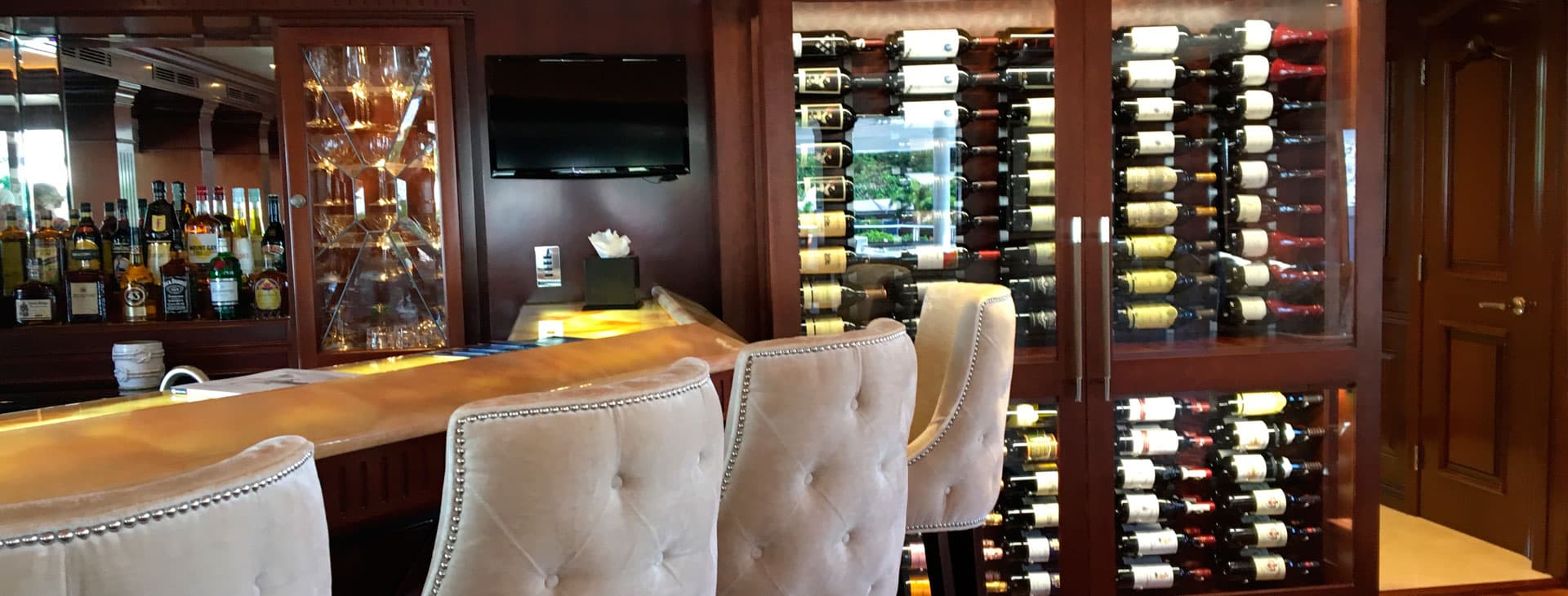Interior of a luxury yacht showing a bar with stools and wine display fridges